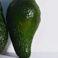Dois abacates encostados em uma superfície branca