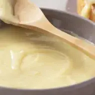 Ganache de Chocolate Branco em uma tigela branca com uma colher de madeira em cima