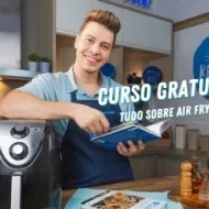 Fotografia mostra um rapaz apoiado sobre uma air fryer, segurando um livro.