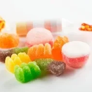 Guloseimas e doces variados em cima de uma mesa branca. A imagem representa os 5 alimentos que não deixam emagrecer. 