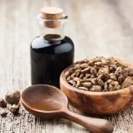 Frasco de vidro com própolis, tigela de madeira com pedaços de própolis e colher de madeira sobre superfície rústica.