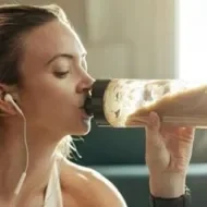 Mulher com roupas de ginástica bebendo um smoothie. A imagem representa os suplementos proteicos.