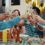 Pessoas brindando em uma mesa e ceia festiva.