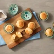 Pãezinhos sobre uma tábua de madeira e bule de chá.