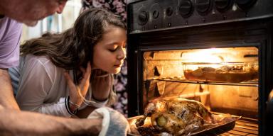 Capa - Ceia de Natal: 20 receitas indispensáveis para seu cardápio! Receitas de Ceia de Natal: Homem colocando frango no forno , ao lado uma menina