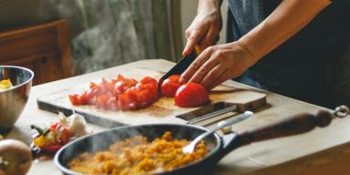 Comida italiana: uma pessoa cortando tomate em cima da tábua de madeira
