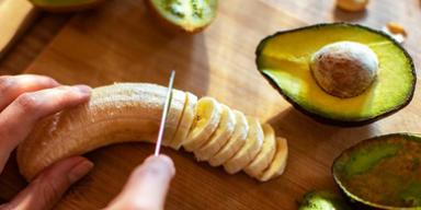 Safra de Março: uma pessoa cortando uma banana, com um abacate cortado do lado Safra de Março: uma pessoa cortando uma banana, com um abacate cortado do lado