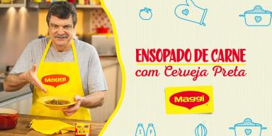 Imagem de um homem alto com bigode de avental segurando um prato amarelo e ao lado direito os dizeres e o logotipo de Maggi