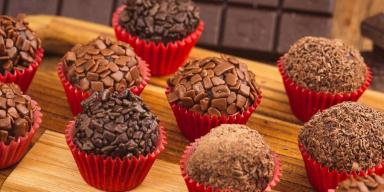 Imagem de brigadeiros gourmet com chocolate granulado em forminhas vermelhas.
