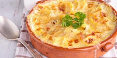 Imagem de uma travessa redonda com uma receita gratinada com queijo e uma folha de salsinha.
