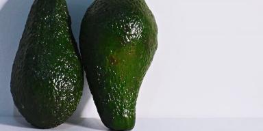 Dois abacates encostados em uma superfície branca
