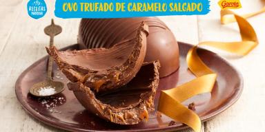 Montagem com um fundo em tons de madeira bem claro e um prato marrom, a foto da receita com as cascas do ovo recheadas ao cen
