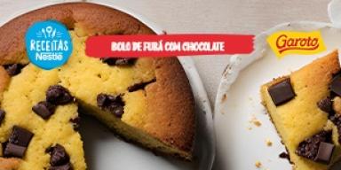 Fotografia mostra um bolo de fubá amarelado com pedaços de chocolates espalhados pela massa.