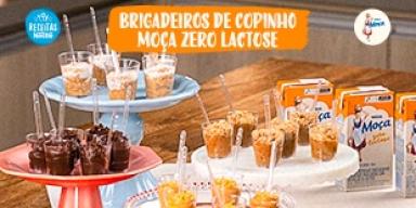 Fotografia mostra quatro tipos de brigadeiros de copinho dispostos sobre uma mesa de madeira.