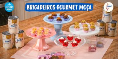 Fotografia mostra quatro tipos de brigadeiros dispostos sobre uma mesa de madeira.
