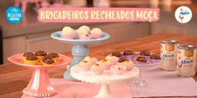 Fotografia mostra quatro tipos de brigadeiros dispostos sobre uma mesa de madeira.