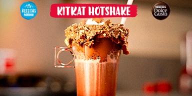Imagem em tom vermelho com o KitKat Hotshake ao centro. Dentro de um copo está uma bebida com chocolate e crocantes de KitKat