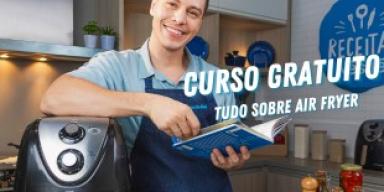 Fotografia mostra um rapaz apoiado sobre uma air fryer, segurando um livro.