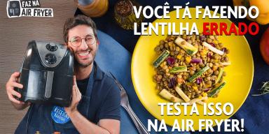Fotografia mostra homem segurando air fryer e prato de lentilha no fundo.