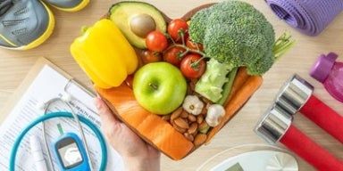 Diabetes Cesta em formato de coração com alimentos saudáveis, entre itens fitness e médicos, representando diabetes.