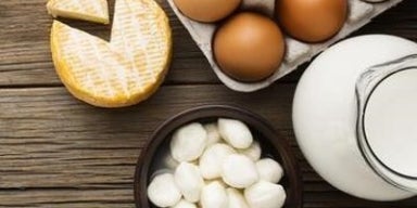 Ovos em bandeja e três tipos de queijo em uma tábua. A imagem representa os alimentos ricos em K2.