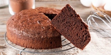 31 receitas de bolo de chocolate simples e deliciosas! Imagem de um bolo redondo de chocolate com uma fatia em evidência.