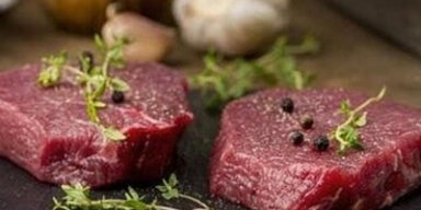 Bife cru de carne vermelha com especiarias, em cima de uma tábua preta. A imagem representa a carne magra.