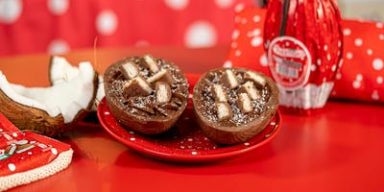 Ovo de Páscoa Prestígio recheado com chocolate e pedaços de coco, decorado com barrinhas Prestígio ao fundo.