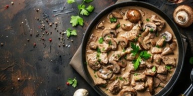 Prato de strogonoff de carne com cogumelos fatiados em molho cremoso, decorado com salsa fresca.