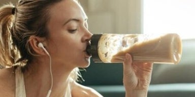 Mulher com roupas de ginástica bebendo um smoothie. A imagem representa os suplementos proteicos.