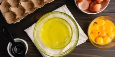 Albumina: o que é e qual a sua função no nosso corpo Texto alt: Claras e gemas de ovo separadas em tigelas sobre mesa de madeira, representando a albumina.