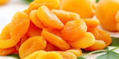 Damasco: benefícios para saúde, valor nutricional e receitas! Damascos desidratados em uma tábua de madeira.