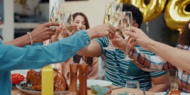 Pessoas brindando em uma mesa e ceia festiva.