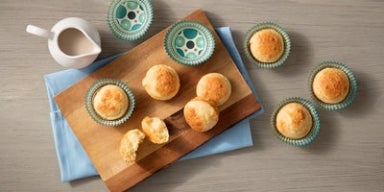 Pãezinhos sobre uma tábua de madeira e bule de chá.