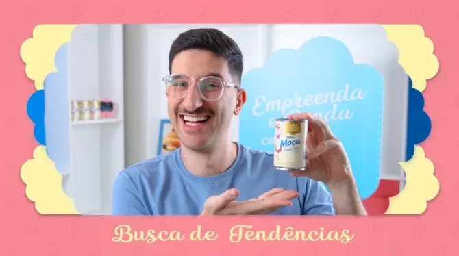 Fotografia com tons rosa, azul e amarelo, mostra um homem sorridente, segurando uma lata de leite condensado.