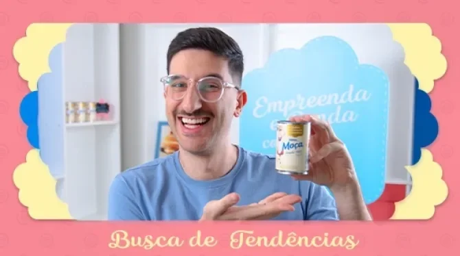 Fotografia com tons rosa, azul e amarelo, mostra um homem sorridente, segurando uma lata de leite condensado.