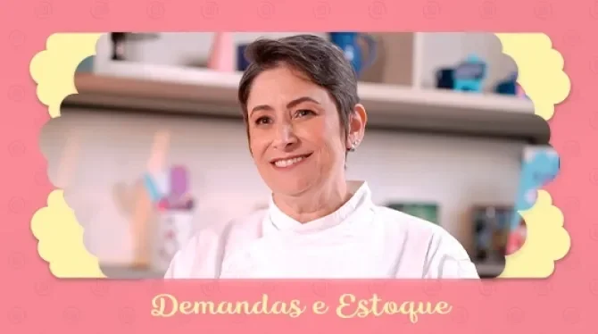 Fotografia com tons rosa, azul e amarelo, mostra uma mulher de cabelo curto, sorridente. Ao fundo um cenário de cozinha.