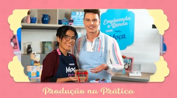 Fotografia com tons rosa, azul e amarelo mostra duas pessoas sorrindo enquanto mostram uma caixinha com brigadeiros.