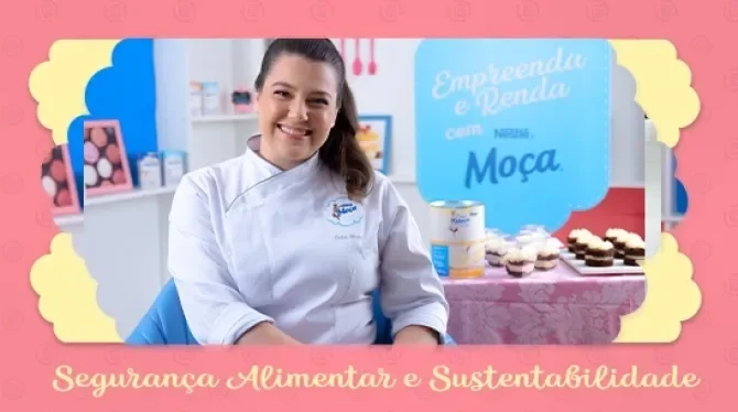 Fotografia com tons rosa, azul e amarelo, com uma mulher de cabelo preso, sorridente. Ao fundo docinhos expostos em uma mesa.