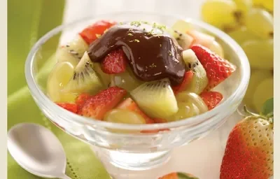 fotografia em tons de verde, contém uma taça transparente com pedaços de morangos, kiwis e ganache por cima fotografia em tons de verde, contém uma taça transparente com pedaços de morangos, kiwis e ganache por cima