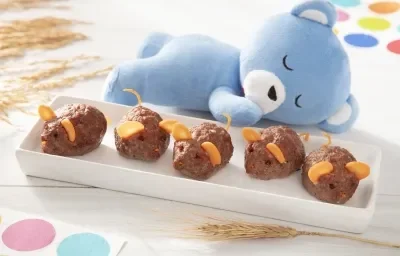 Foto da receita de Bolinho de Carne. Observa-se um recipiente branco retangular com os bolinhos em forma de ratinho em cima.