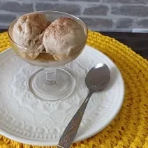 Imagem da receita de Sorvete nutritivo de banana com 3 ingredientes, em um prato branco, sobre uma mesa e ao lado os talheres