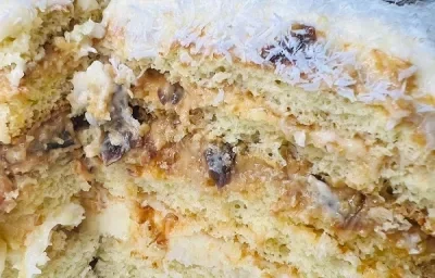 Foto da receita de Massa de Bolo de Leite Ninho. Observa-se um bolo de 3 camadas com doce de leite, ameixa e coco na cobertura. Foto da receita de Massa de Bolo de Leite Ninho. Observa-se um bolo de 3 camadas com doce de leite, ameixa e coco na cobertura.
