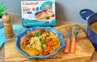 Fotografia em tons alaranjado e azul de um pranto servindo arroz e lombo de bacalhau com pimentões. Fotografia em tons alaranjado e azul de um pranto servindo arroz e lombo de bacalhau com pimentões.