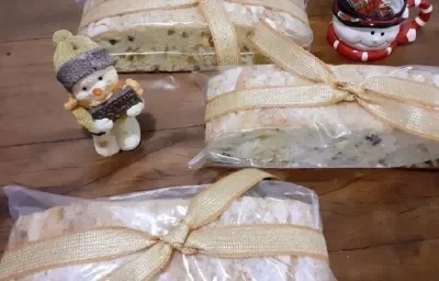 Foto da receita de bolo de natal servida em três porções sobre uma mesa de madeira com decorações de natal como bonecos de neve