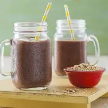foto tirada de dois copos transparentes e ambos contém a vitamina de Açaí, à frente contém um potinho redondo vermelho com Neston