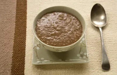 Fotografia de um mingau de chocolate servido em uma tigela, em tons verdes e estampa de flores branca. Fotografia de um mingau de chocolate servido em uma tigela, em tons verdes e estampa de flores branca.