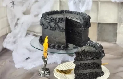 Foto da receita de Bolo de Veludo Preto. Observa-se um bolo alto preto decorado de preto, com uma decoração de Dia das Bruxas. Foto da receita de Bolo de Veludo Preto. Observa-se um bolo alto preto decorado de preto, com uma decoração de Dia das Bruxas.