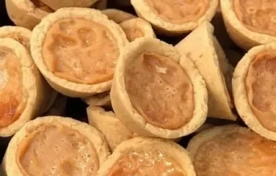 Foto em tons de bege e marrom claro da receita de empadinha de leite moça servida em diversas porções dispostas aleatoriamente uma sobre as outras Foto em tons de bege e marrom claro da receita de empadinha de leite moça servida em diversas porções dispostas aleatoriamente uma sobre as outras