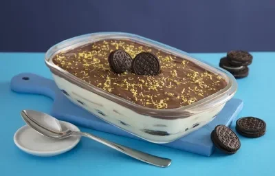 Foto da receita de pave de negresco de limao siciliano. Observa-se uma travessa de vidro transparente em um fundo de dois tons de azul com biscoitos negresco decorando Foto da receita de pave de negresco de limao siciliano. Observa-se uma travessa de vidro transparente em um fundo de dois tons de azul com biscoitos negresco decorando